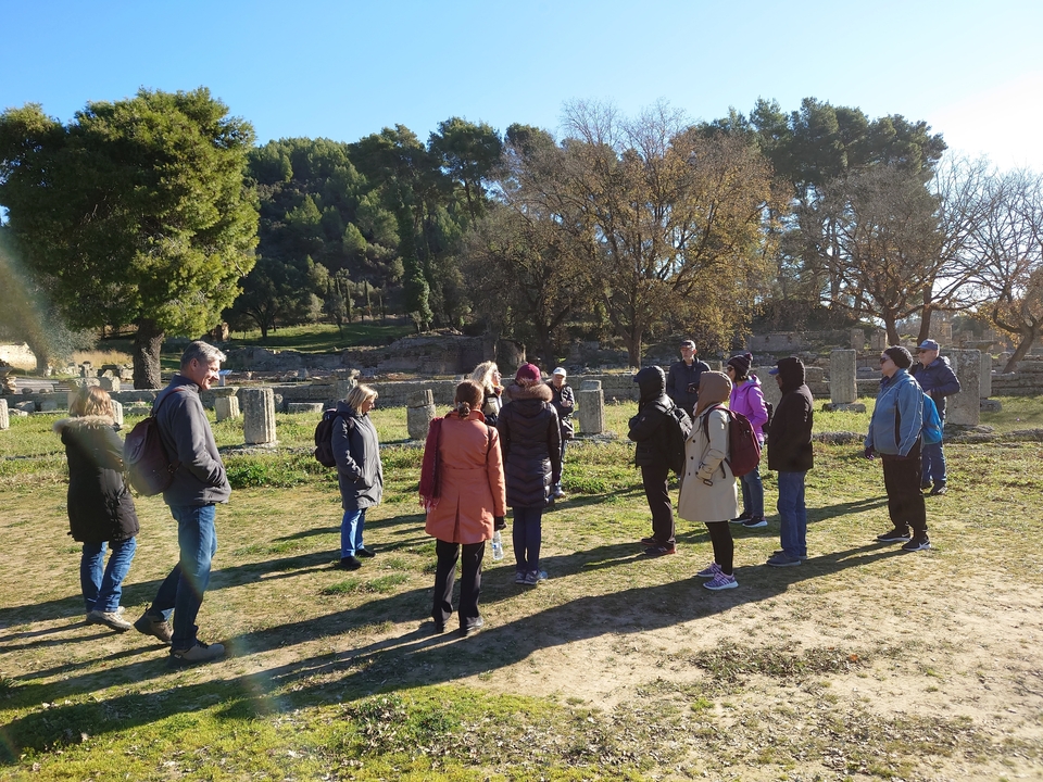 Groupe de personnes participant à une visite guidée parmi des ruines antiques.
