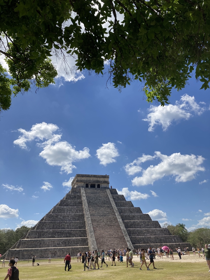 Sommet de pyramide avec un ciel bleu vif et des nuages blancs cotonneux.