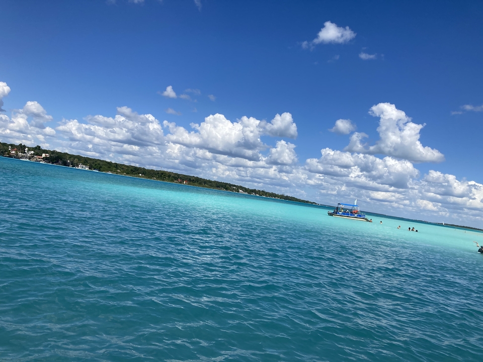 Eaux turquoise d'un lagon sous un ciel bleu avec des nuages.