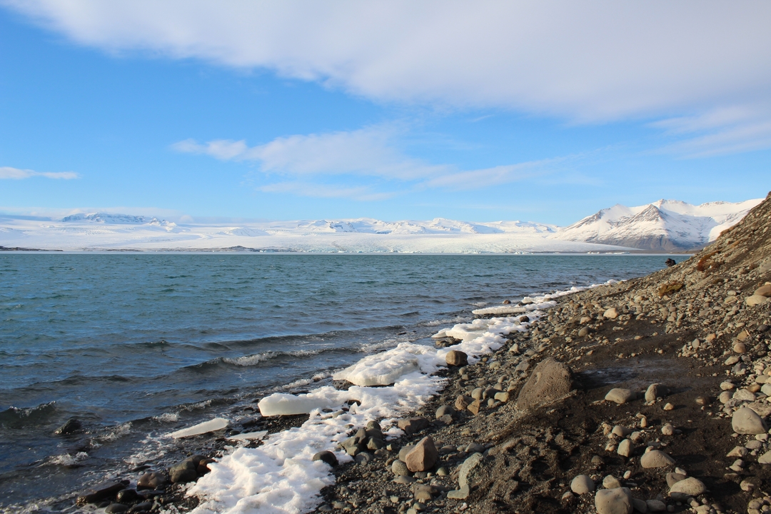 Rivage rocheux avec des eaux glacées et des montagnes enneigées au loin