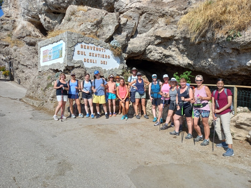 Hiking group on a trail with a cave and sign