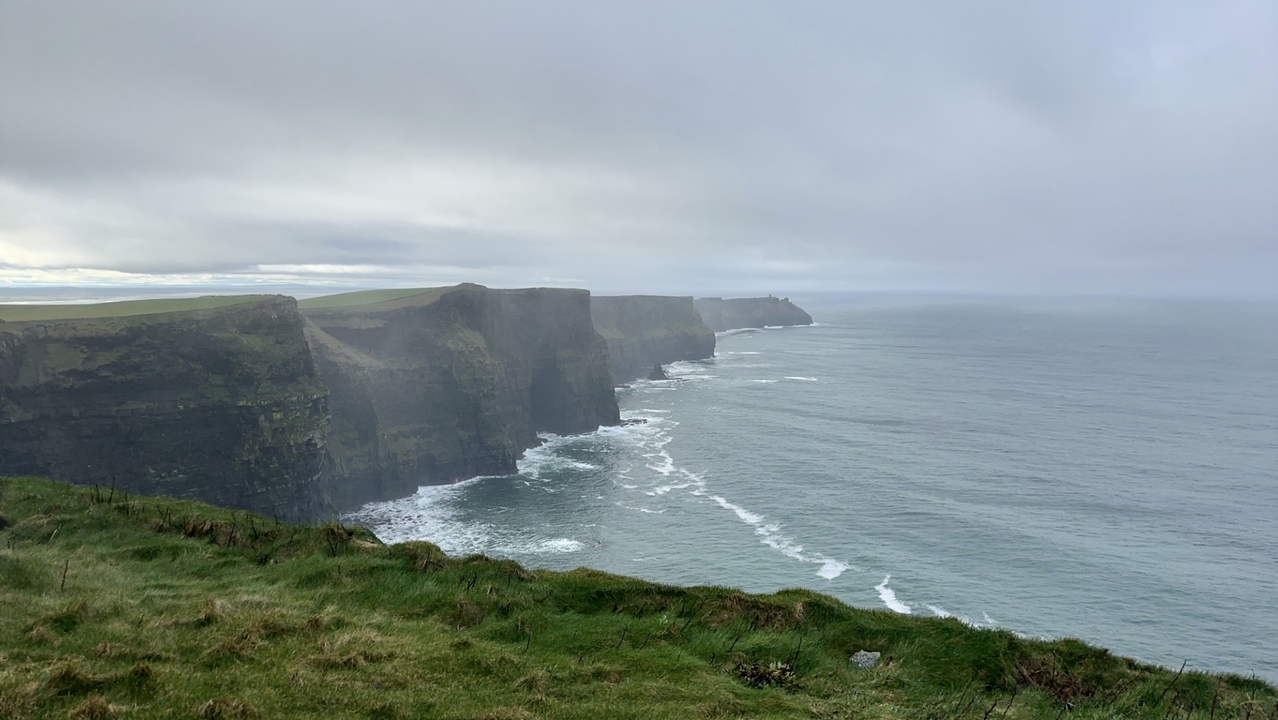 Falaises de Moher le long de la côte sous un ciel nuageux.