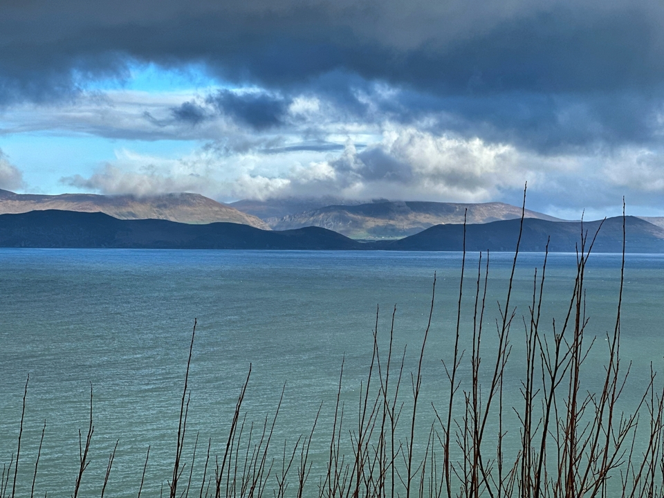 Une vue panoramique d'un lac avec des montagnes au loin et un ciel nuageux.