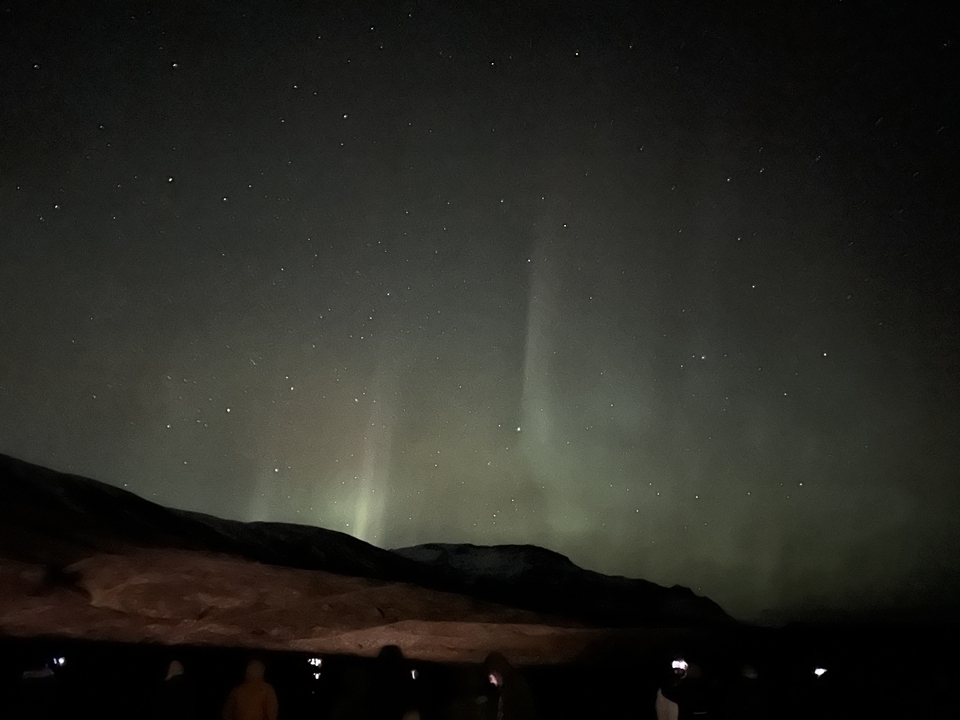 Un ciel nocturne présentant de faibles aurores boréales avec des étoiles.