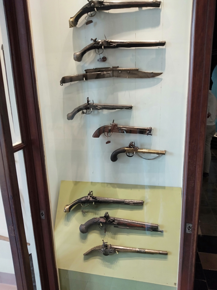 Ausstellung historischer Pistolen in einer Vitrine.