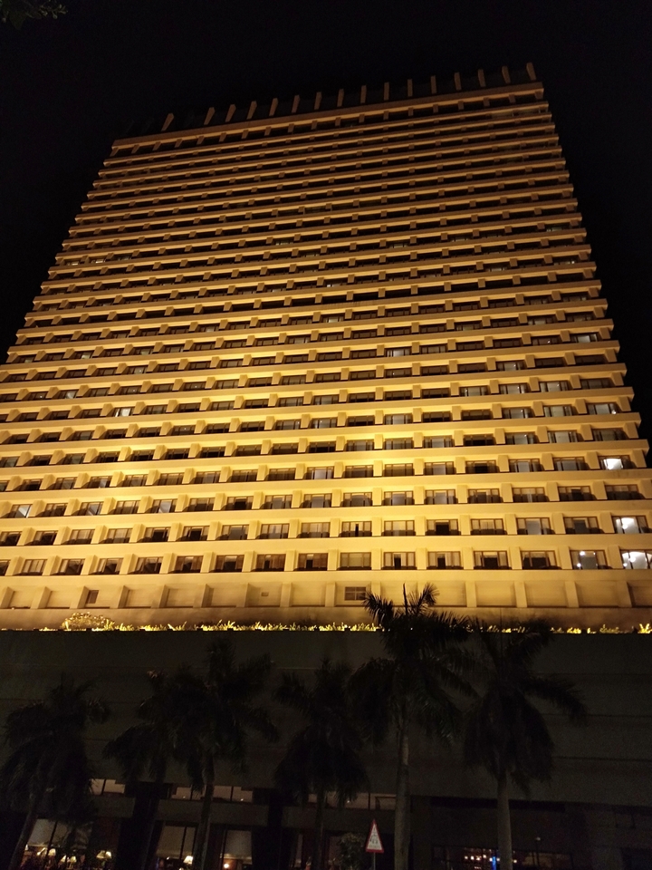 Hochhaus mit zahlreichen Balkonen, die nachts beleuchtet sind.