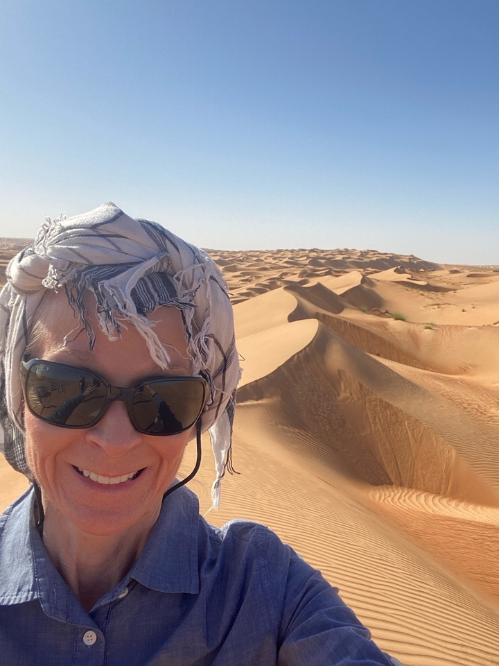 Selfie avec en arrière-plan des dunes de sable du désert sous un ciel lumineux.