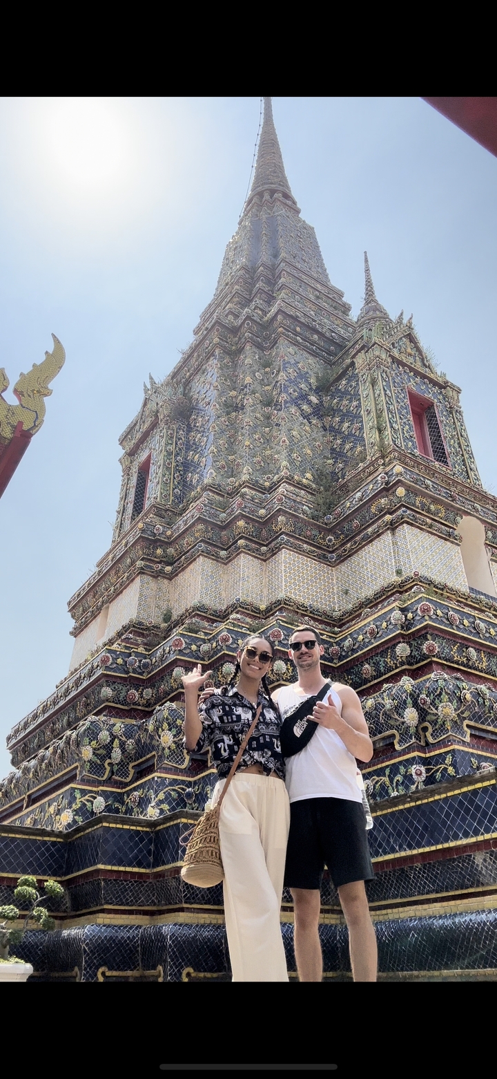 Couple posant devant la façade élaborée d'un bâtiment.