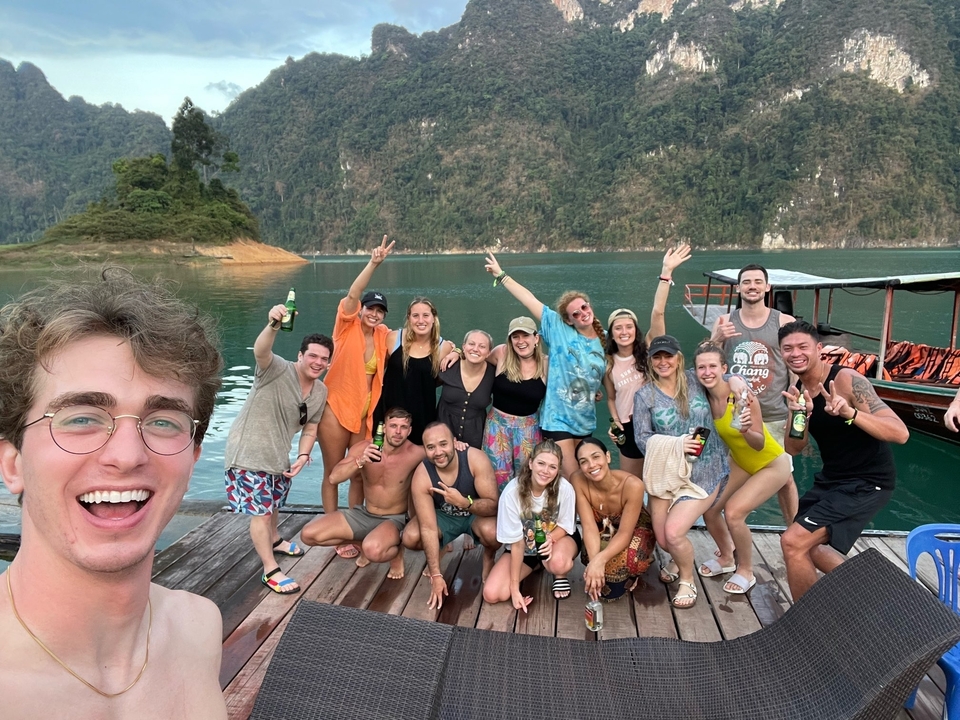 Large group enjoying a scenic view by a lake with mountains.