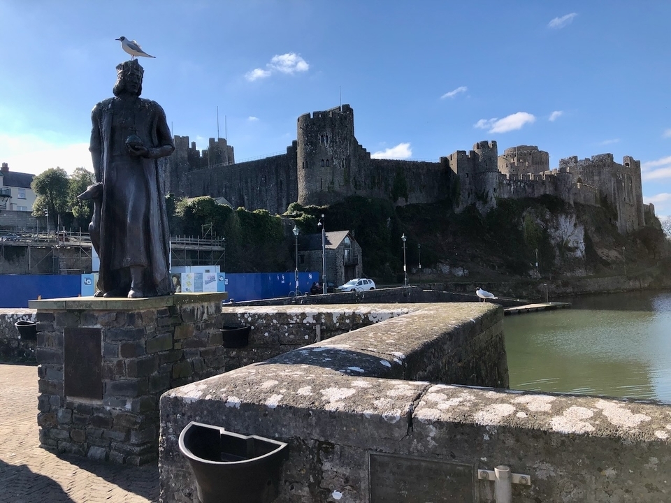 Un château historique au bord d'un plan d'eau avec une statue.