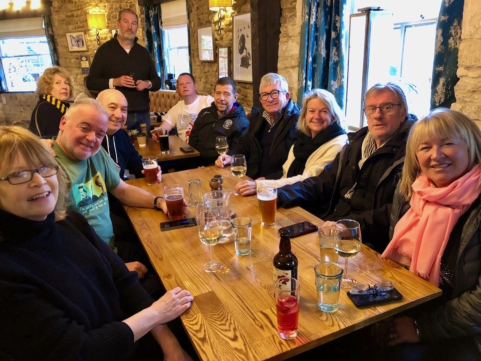 Un groupe de personnes qui savourent des boissons à une table en bois.