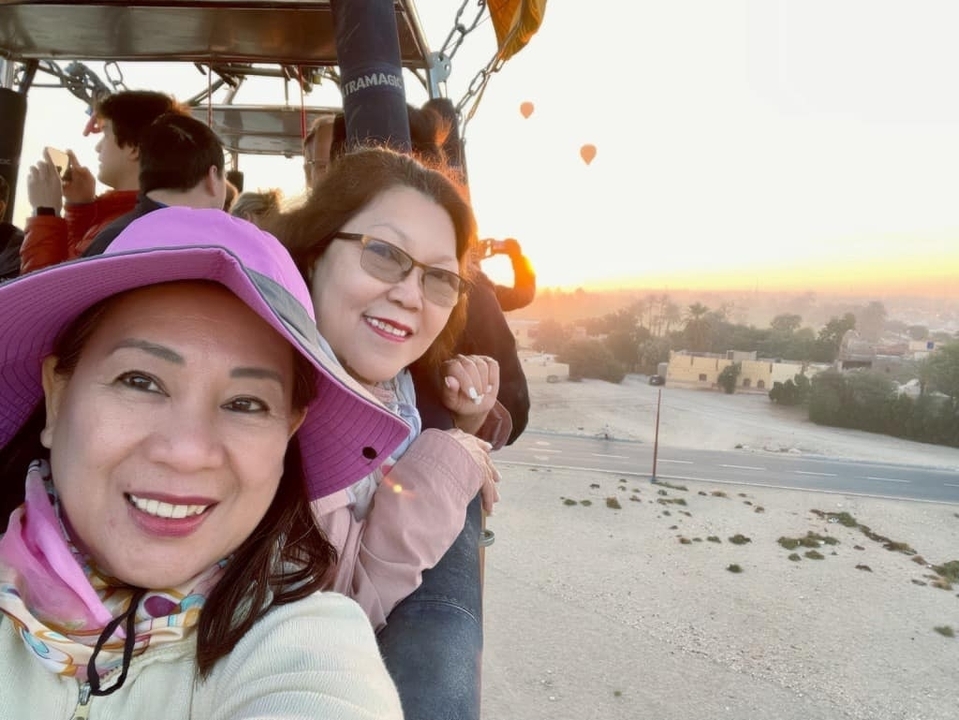 Deux personnes dans une montgolfière avec vue sur le lever du soleil et le désert.