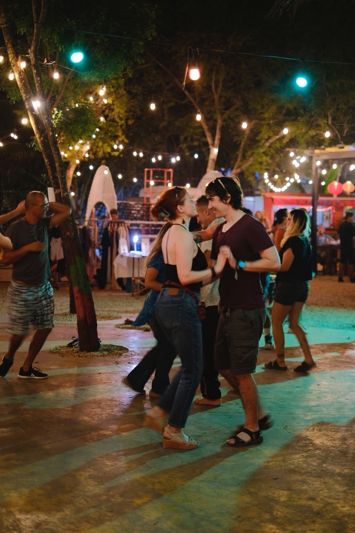 Des gens qui dansent dans un cadre festif en plein air avec des éclairages.