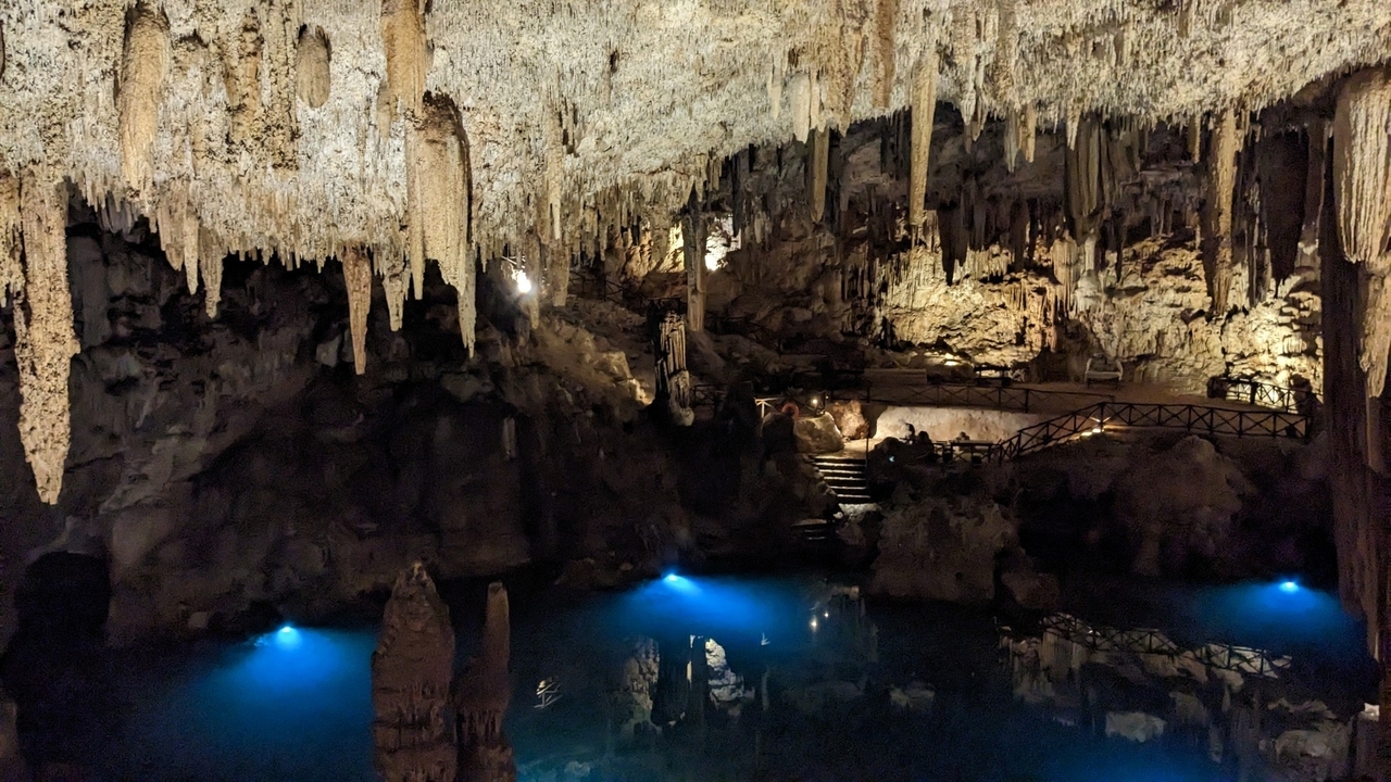 Une vue à couper le souffle à l'intérieur d'une grotte avec des stalactites et un bassin d'eau calme.
