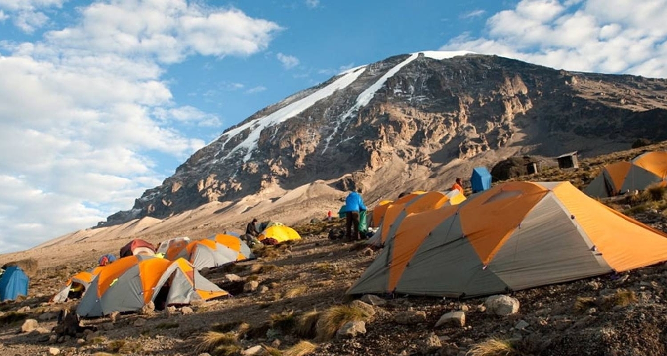 Site de camping avec des tentes au pied de la montagne.