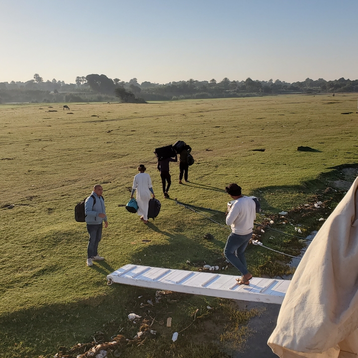 Des gens marchant à travers un champ herbeux près d'une rivière.