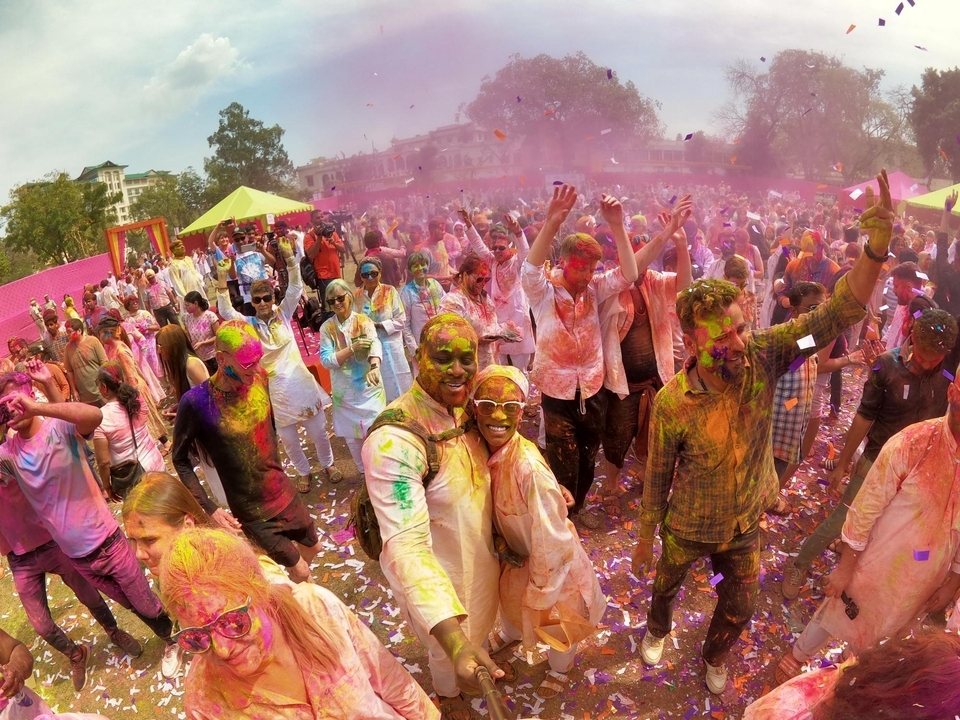 Grand groupe célébrant Holi avec des couleurs vives et des expressions joyeuses.