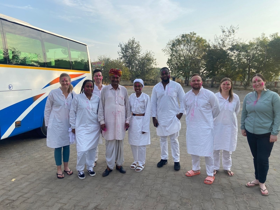 Groupe de personnes en tenue traditionnelle posant devant un bus.