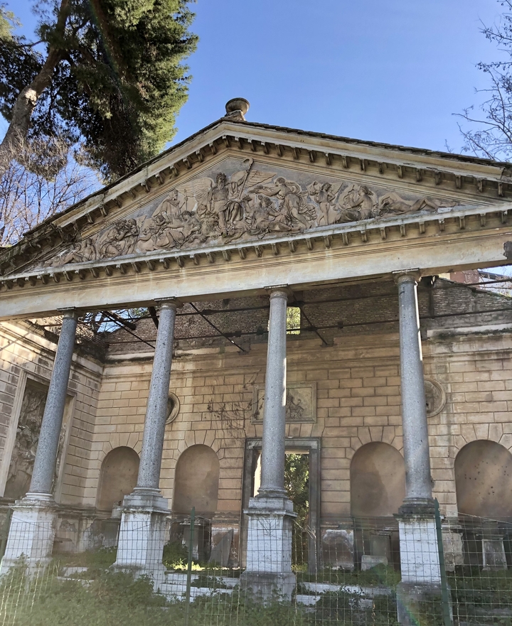 Bâtiment antique avec colonnes décoratives et fronton.