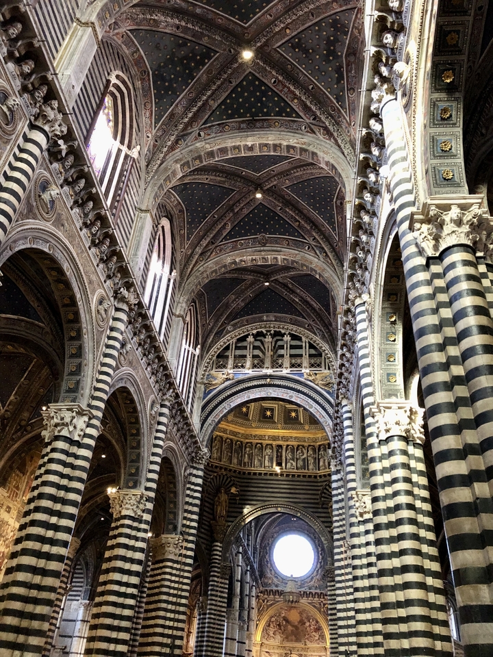 Intérieur de cathédrale avec colonnes rayées et voûtes.