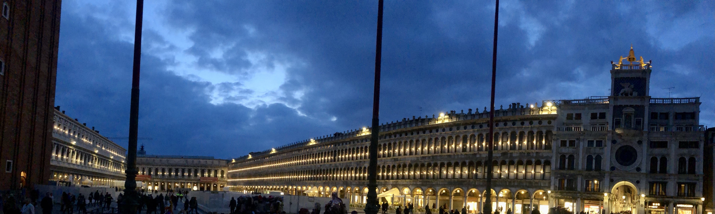 Grand bâtiment aux arches illuminées sous un ciel crépusculaire.