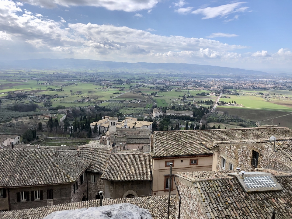 Vue panoramique sur les champs et bâtiments historiques depuis une colline.