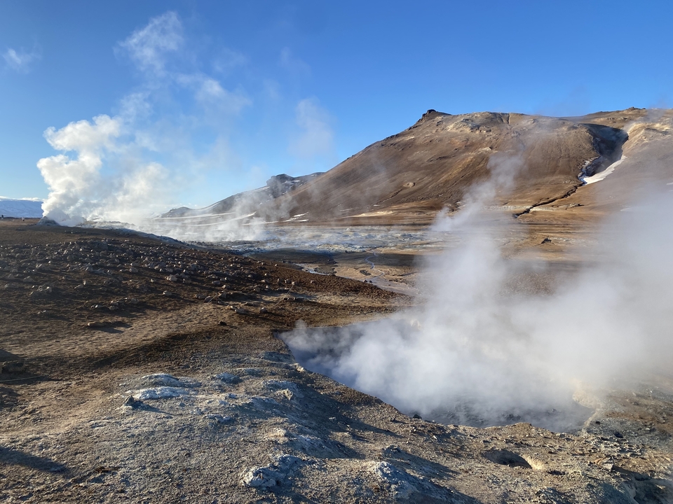 Geothermal area with steam rising from the ground.