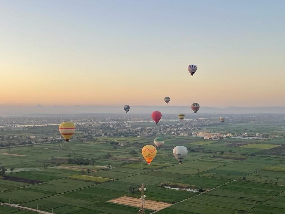Montgolfières flottant au-dessus des champs et des petits villages à l'aube.