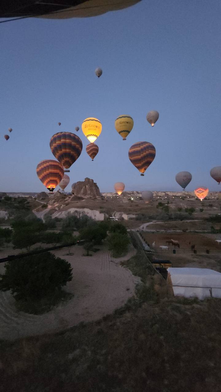 Plusieurs montgolfières flottant au-dessus d'un paysage à l'aube.