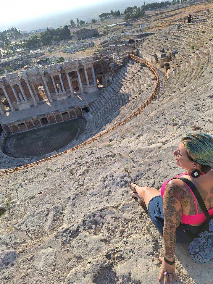 Personne qui pose dans un amphithéâtre antique.