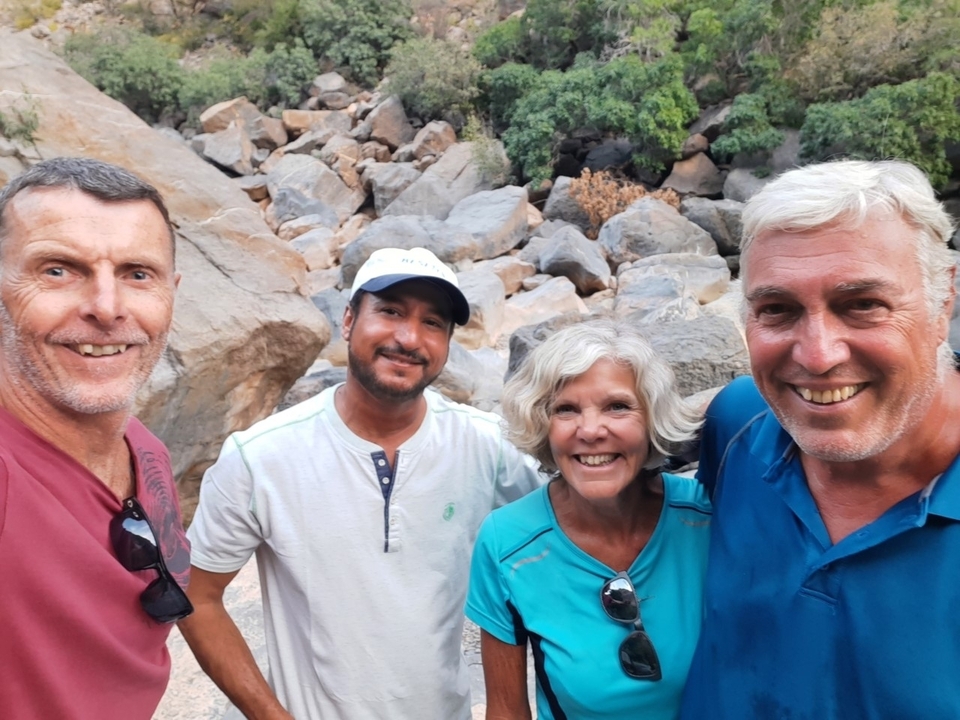Groupe de quatre amis souriants dans une zone rocheuse.