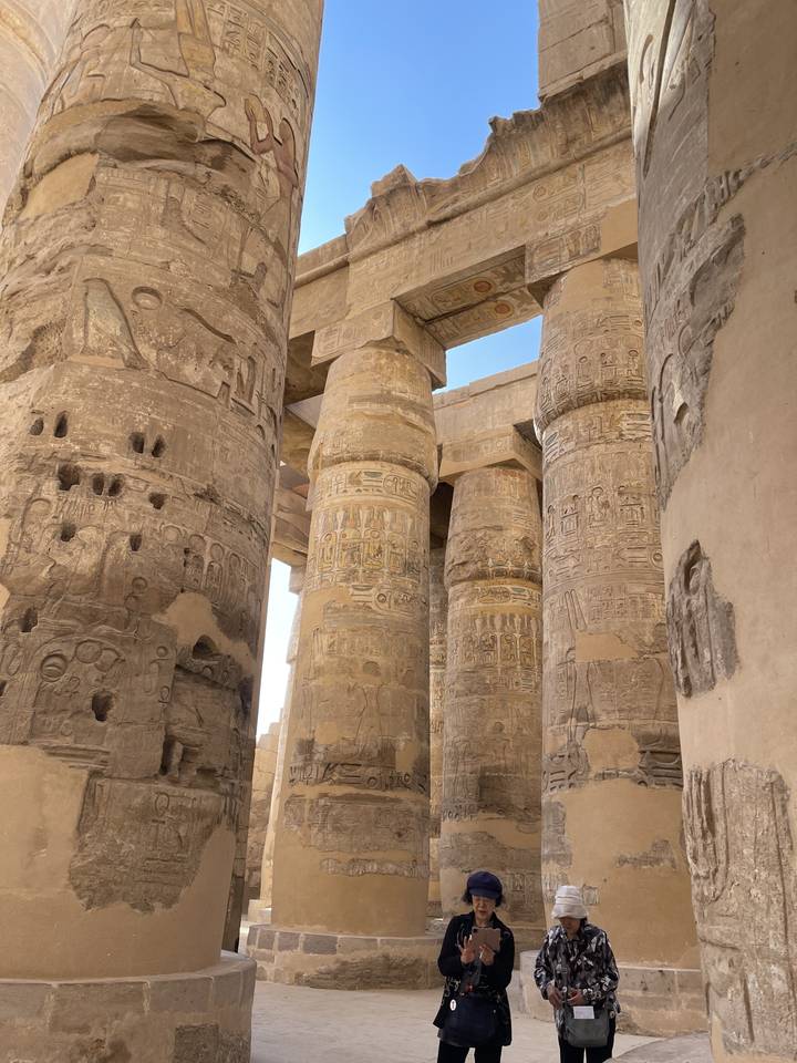 Grandes colonnes avec des sculptures complexes et quelques personnes.