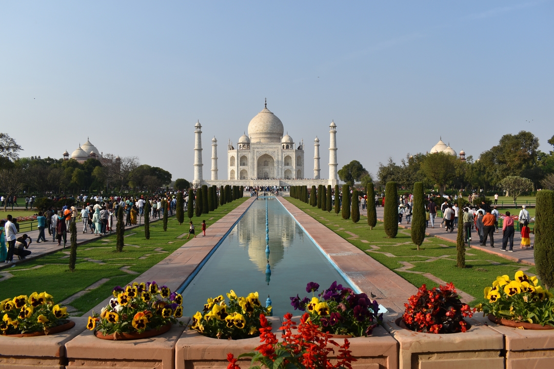 Le Taj Mahal avec son bassin réfléchissant et ses jardins remplis de monde.