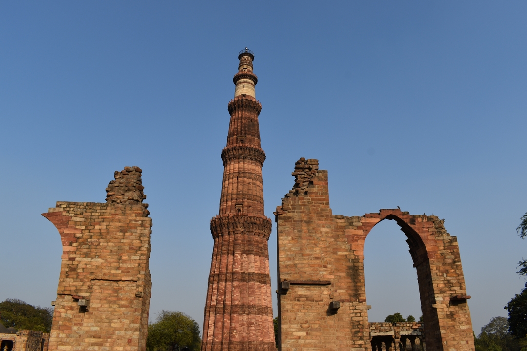 Tour ancienne et haute avec des sculptures complexes et des ruines d'arche.