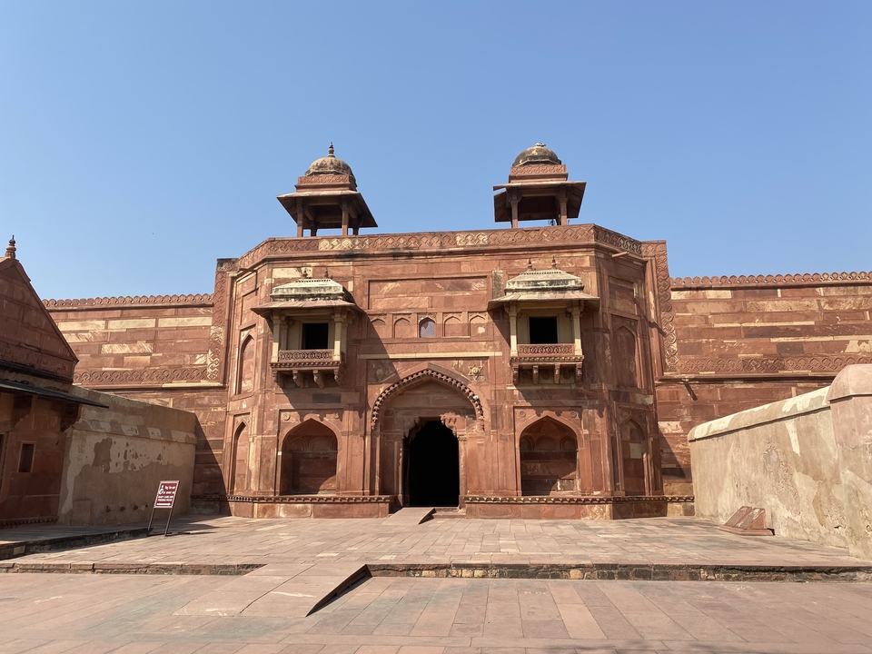 Bâtiment historique en grès rouge avec des sculptures complexes.