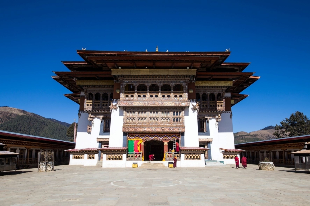 Structure traditionnelle bhoutanaise avec un design vibrant et un ciel bleu clair.