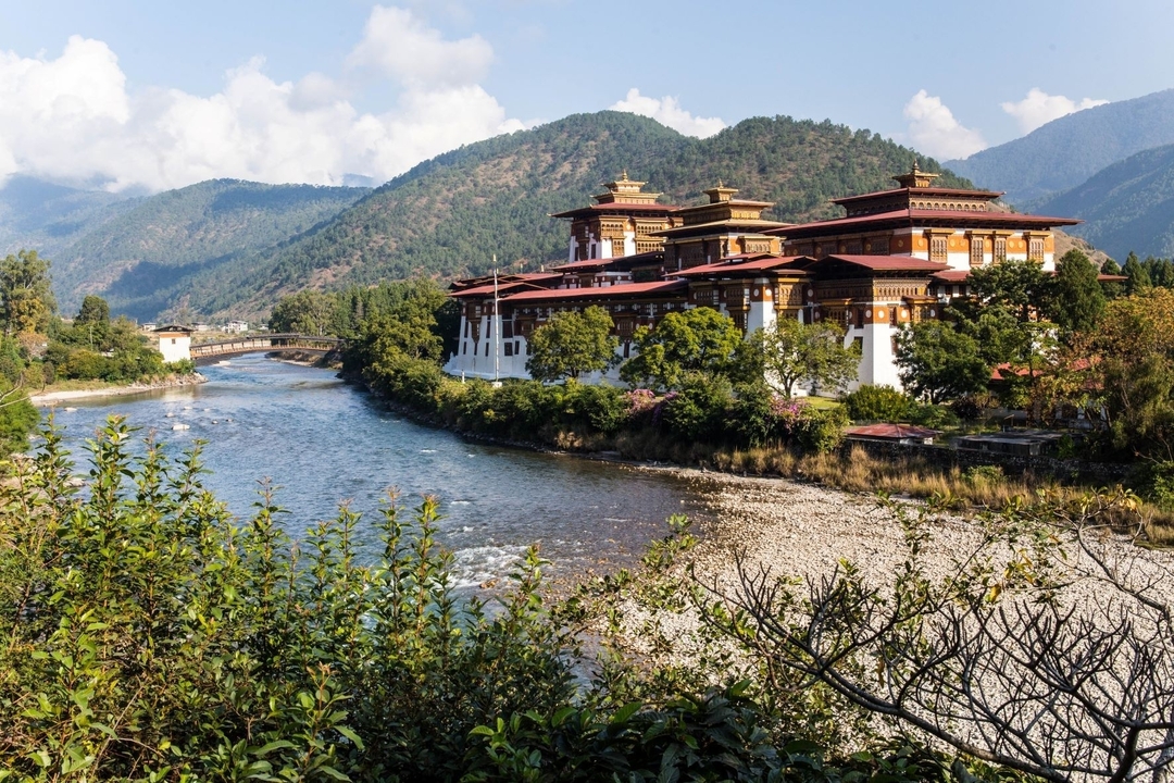 Punakha Dzong avec une rivière au premier plan et des montagnes en arrière-plan.