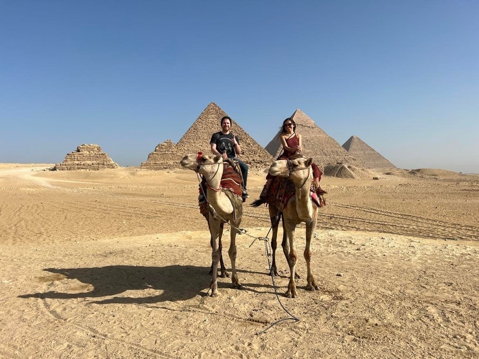 Deux personnes sur des chameaux devant les Pyramides de Gizeh.