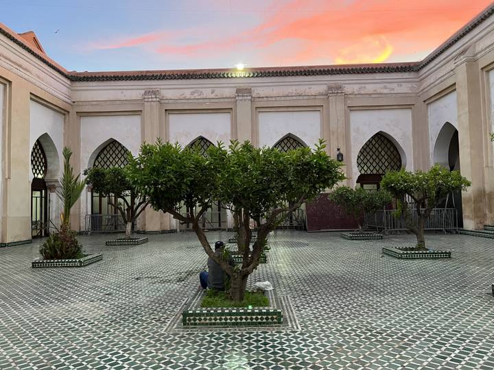 A courtyard with trees and arches during sunset.