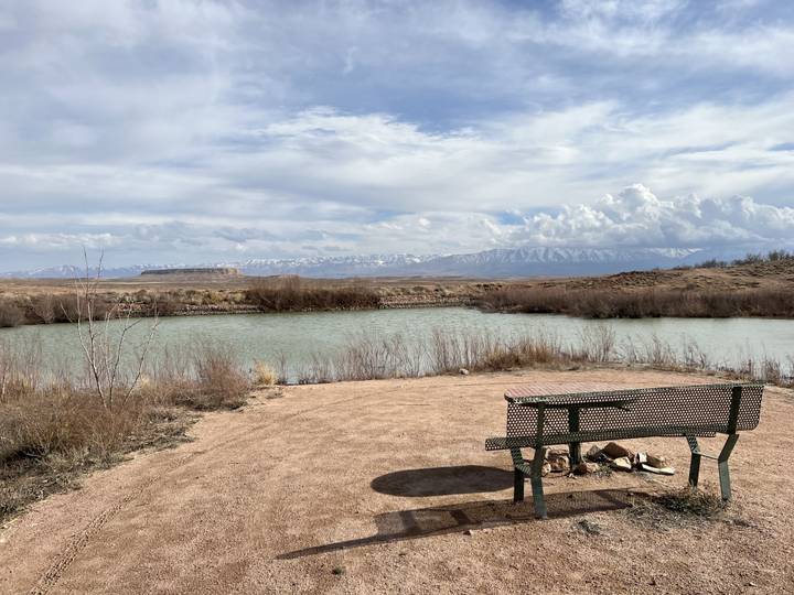 Bench by a river with distant mountains