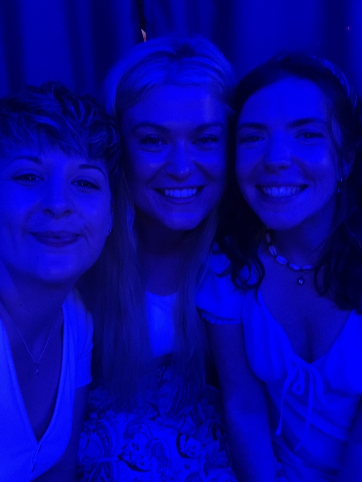Three people under blue lighting.