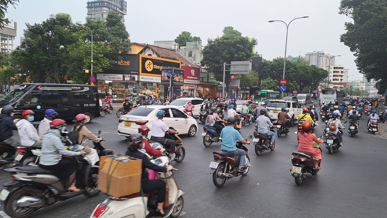 Scène de rue animée avec des motos et des bus.