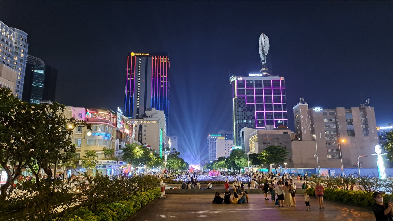 Paysage urbain nocturne animé avec des gratte-ciel vivement éclairés.