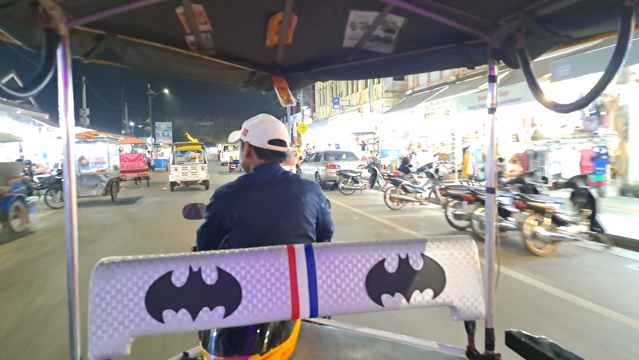 Vue depuis un tuk-tuk dans une rue de marché animée.