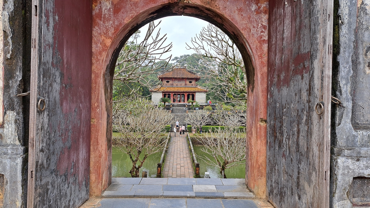 Portique historique encadrant une vue sur un temple antique.