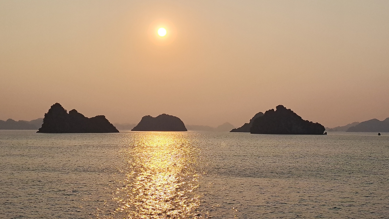 Coucher de soleil sur la mer avec des formations d'îles en silhouette.