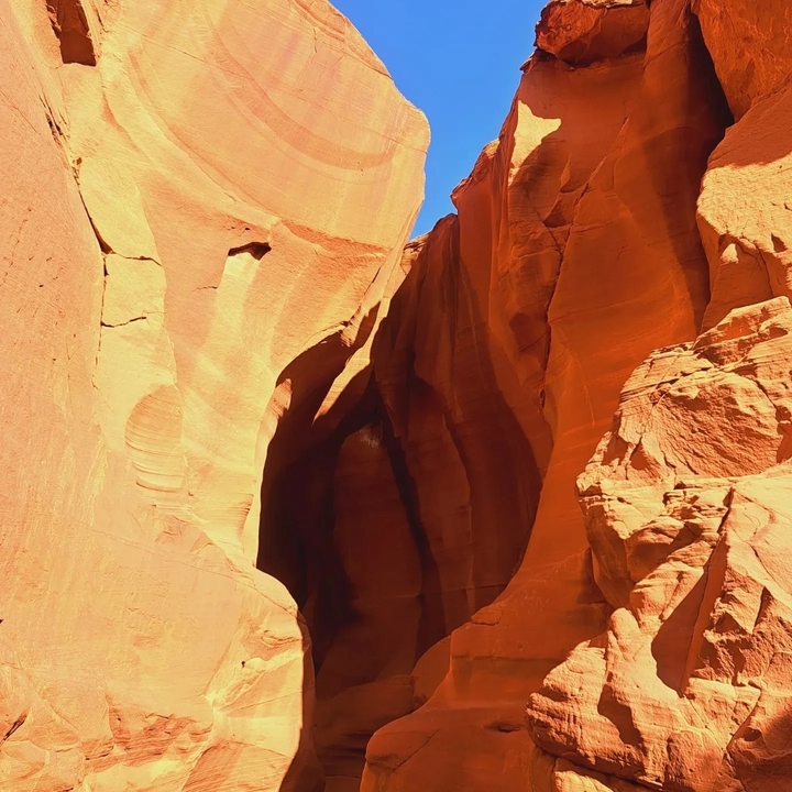 Étroit canyon aux parois de roche rouge et au ciel bleu.