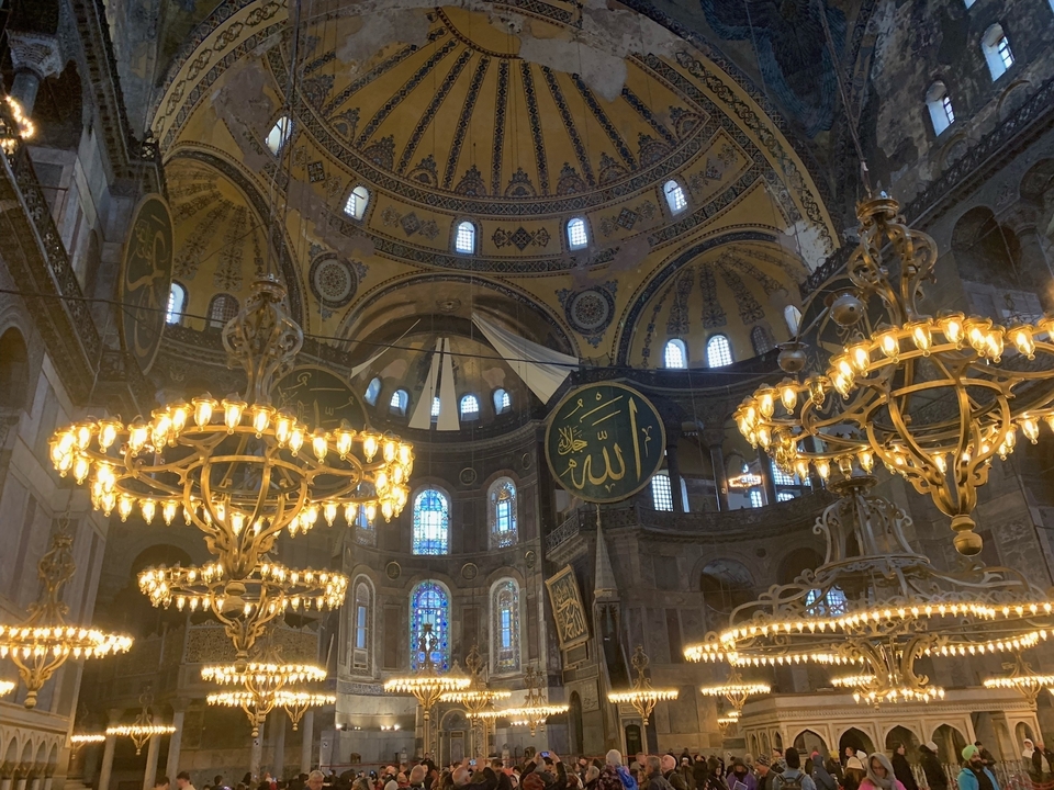 Intérieur complexe d'une mosquée avec des lustres élaborés.