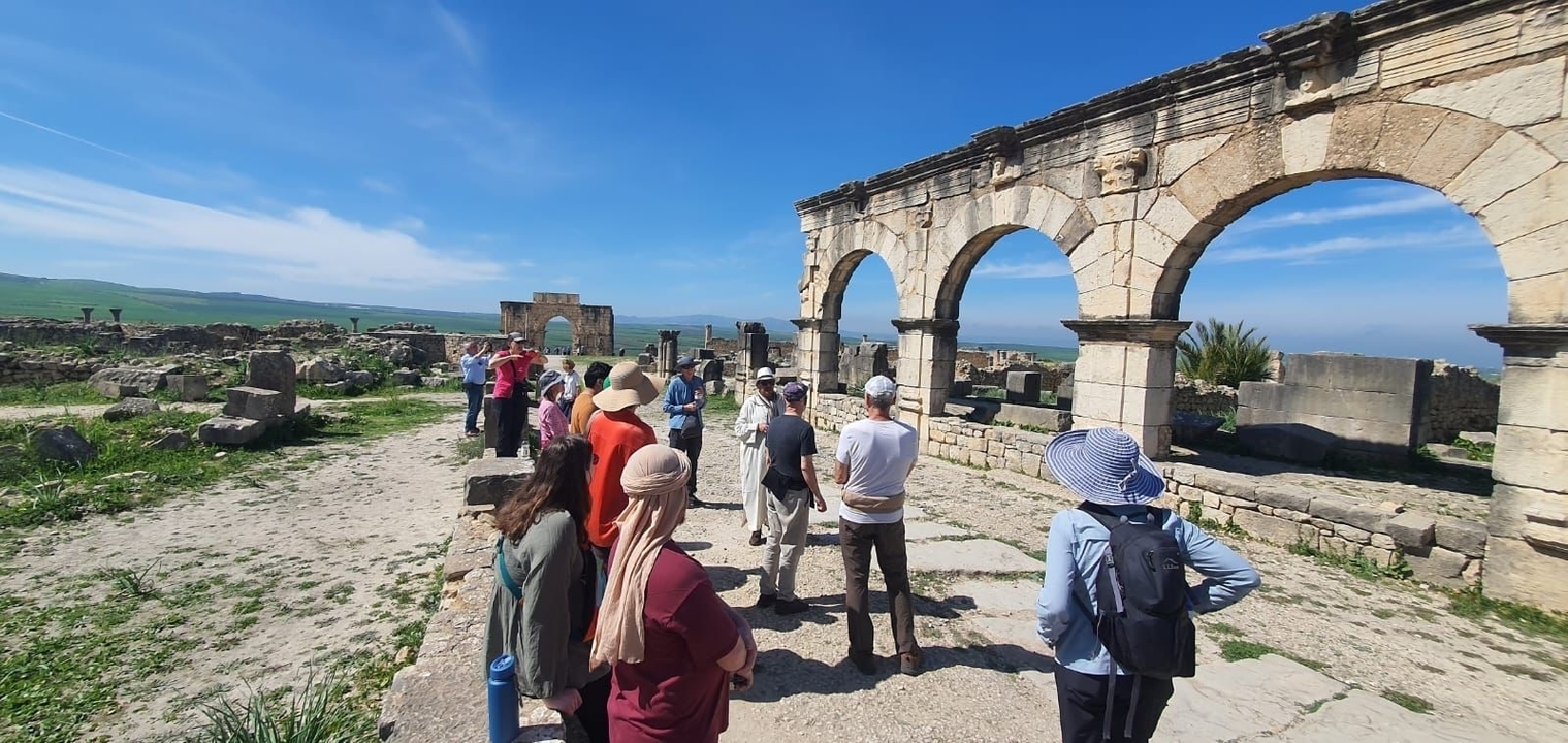 Des touristes explorant des ruines antiques avec des arcs.