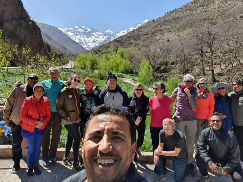 Groupe de personnes posant avec des montagnes enneigées en arrière-plan.